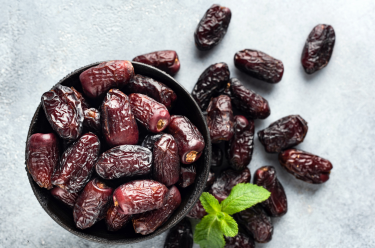 Photo of a bowl of dates and a piece of mint for decoration