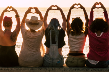 Group of women at the beach with hands in the air